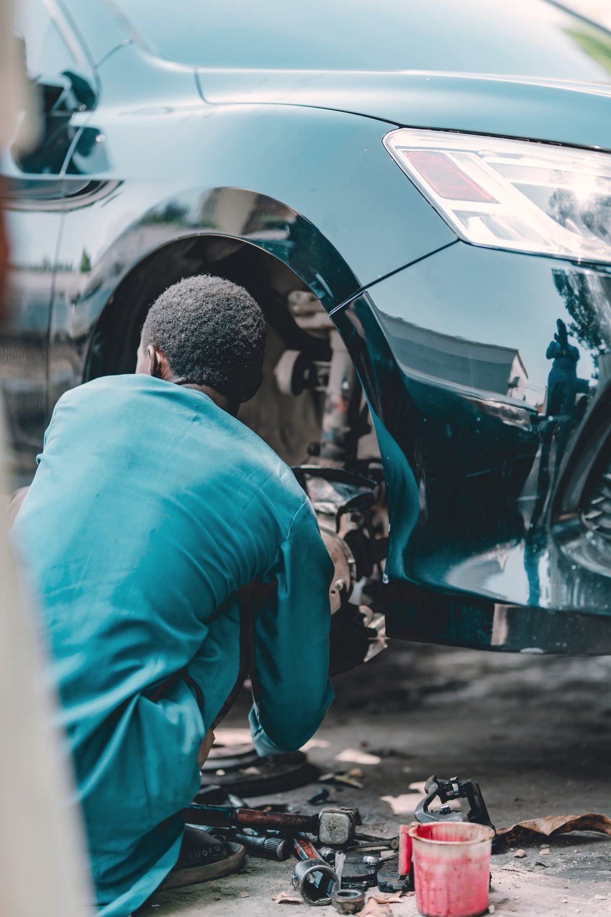 A technician working on the front brake of a car in the shop