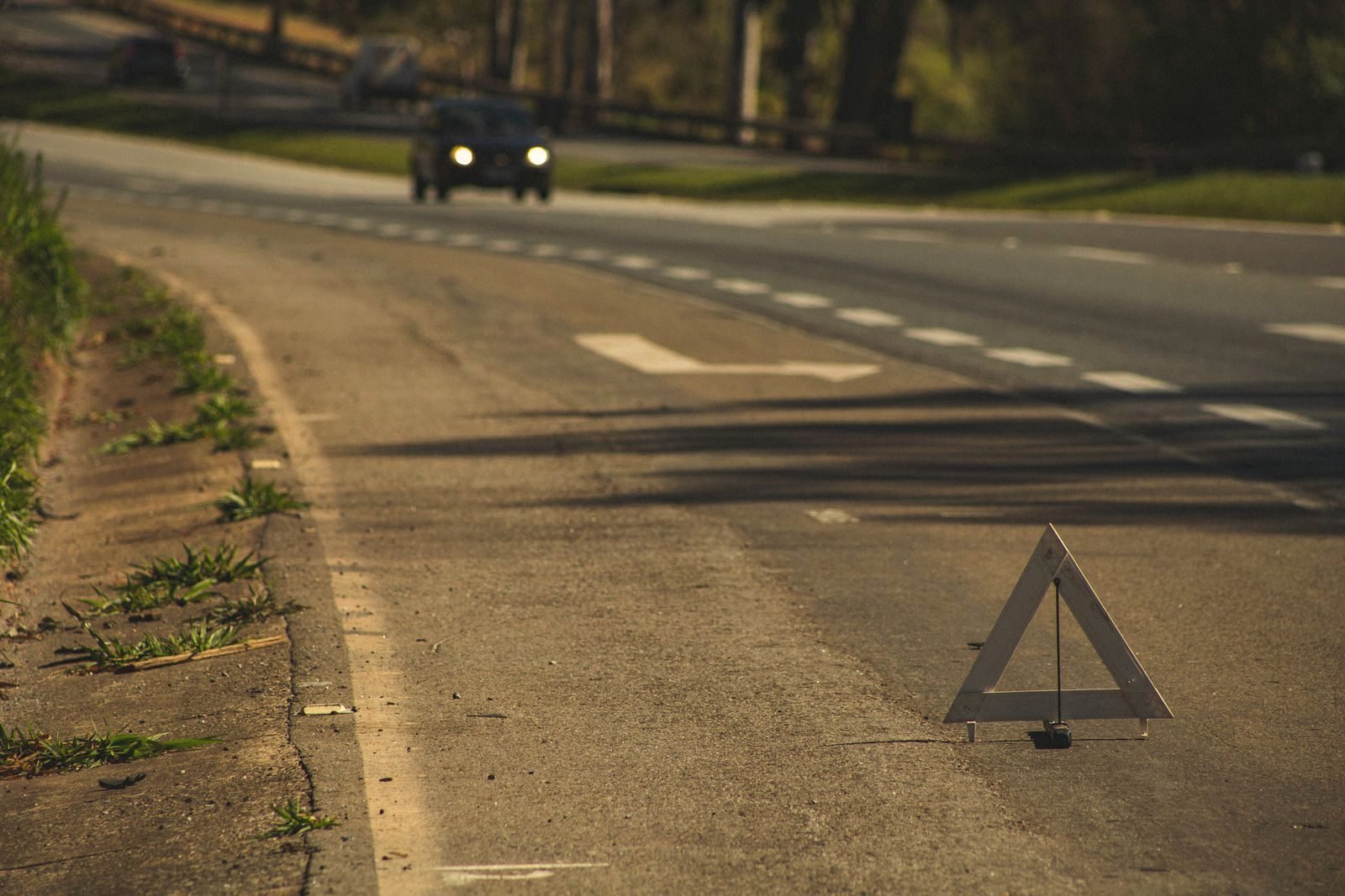Oncoming headlights on a country road near a warning sign