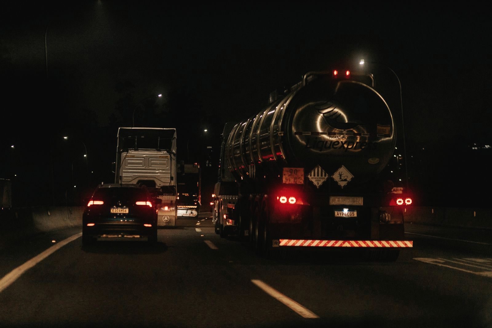 Taillights of traffic trailing down a dark highway at night