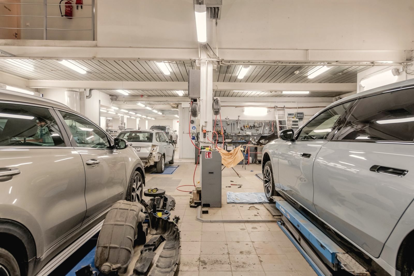 The interior of a repair shop with several vehicles raised for service